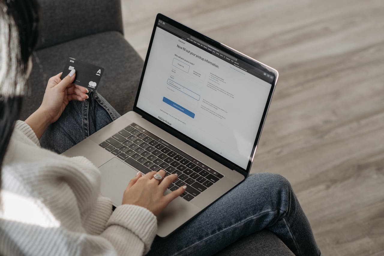 Close-up of a woman using a laptop for online shopping and holding a credit card in hand.